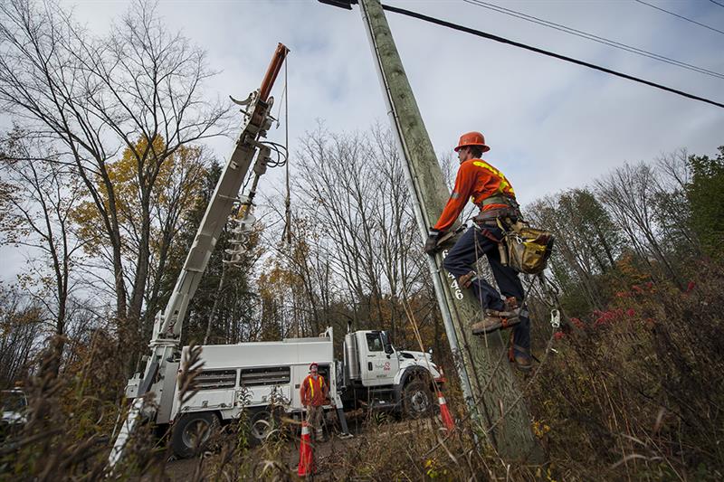 photo of a Hydro One crew using equipment to hold a wooden distribution pole