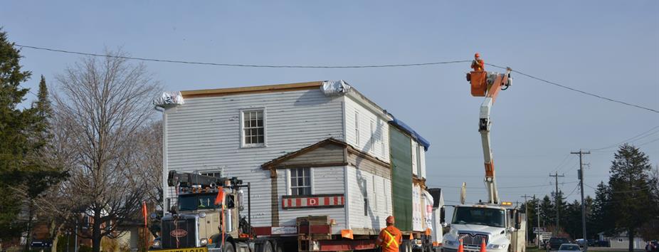 photo of a large vessel being moved under power lines on a street