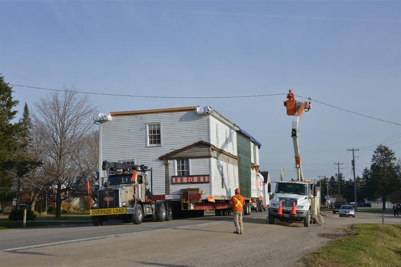 photo of a large vessel being moved under power lines on a street