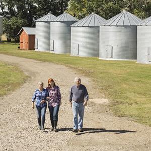 Image a two women and a man walking along the road at an Agribusiness 