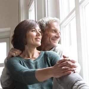 photo of a man and woman snuggling near a window