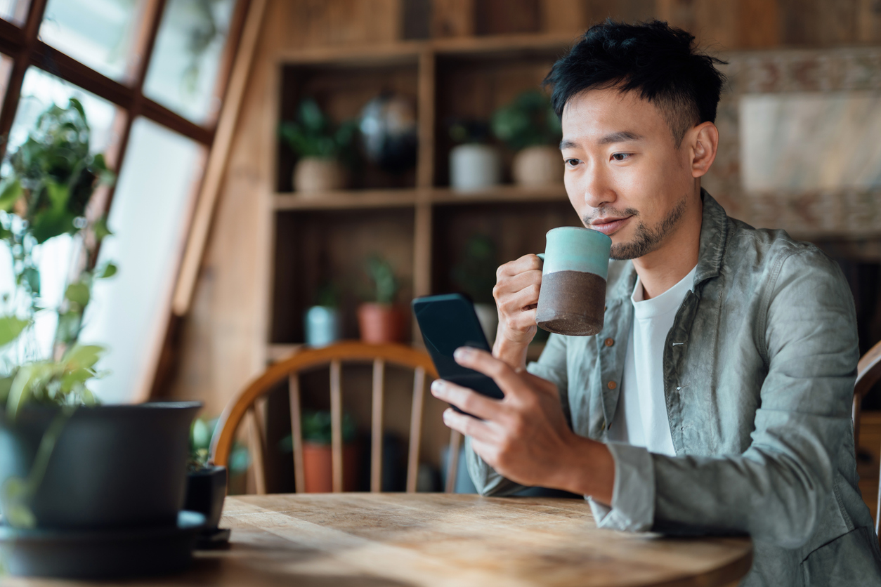 Man using smartphone while drinking coffee