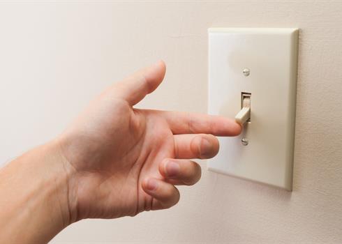 Image of a hand turning on a light switch