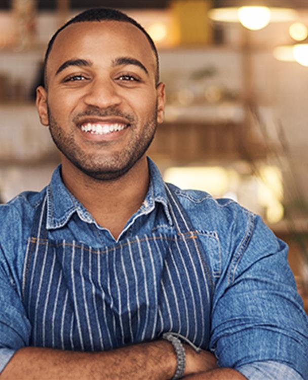 a man standing with his arms crossed in the middle of a restaurant