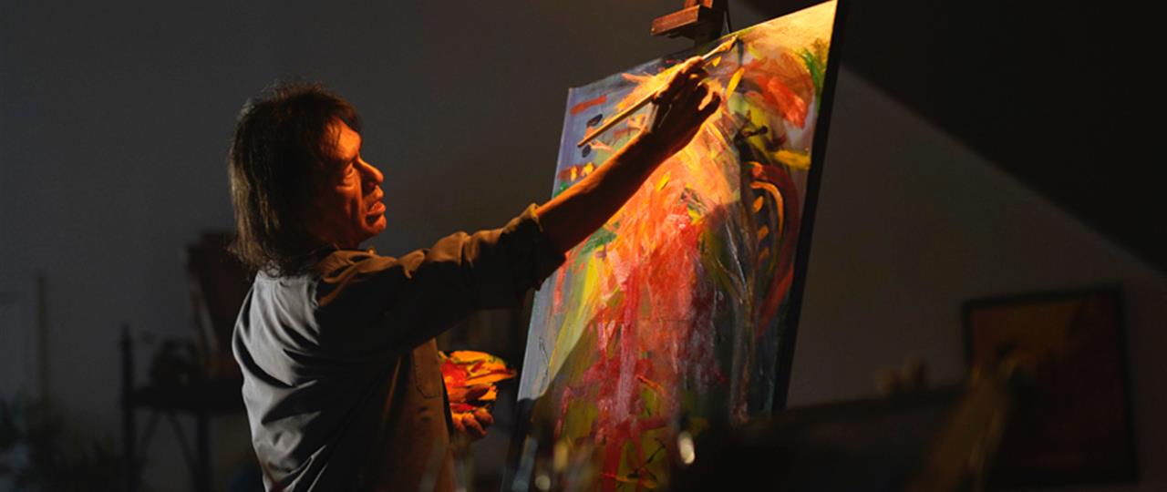 photo of a First Nations artist painting in his studio