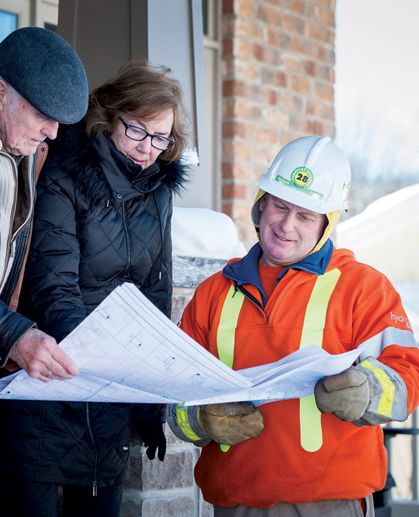 a customer lookng at blue prints outside in the snow with a Hydro One employee