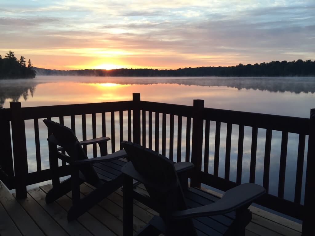 photo of a sunset view from a deck overlooking a lake in cottage country