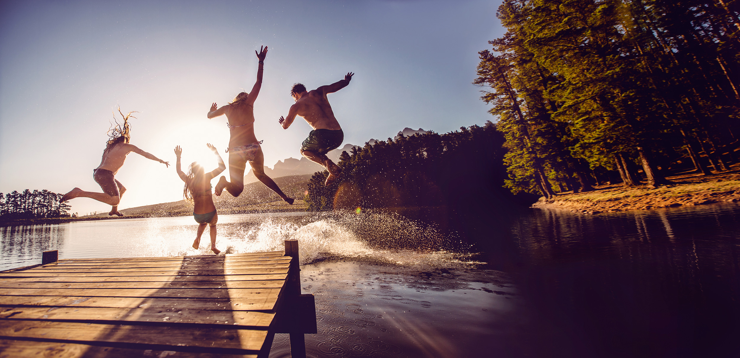 photo of teens jumping off of a dock at summer camp