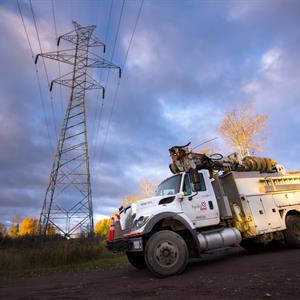 photo of a Hydro One vehicle in front of a transmission tower