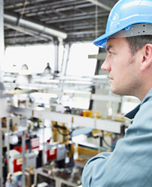 a man looking at notes standing in a factory